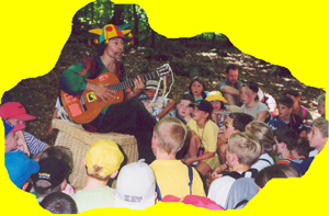 Foto Micha spielt Gitarre und singt mit Kindern im Wald